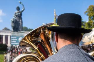 Musikant spielt vor der Bavaria im Hintergrund auf