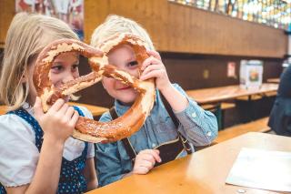 Zwei Kinder mit Wiesnbrezn in einem Festzelt auf dem Oktoberfest