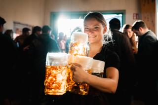 Bedienung trägt mehrere Maß Bier zu den durstigen Gästen