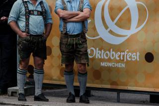 Zwei Männer in Bayerischer Tracht stehen vor einem Oktoberfest-Banner